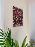 Abstract multicolored artwork on a wall with green plants in the foreground